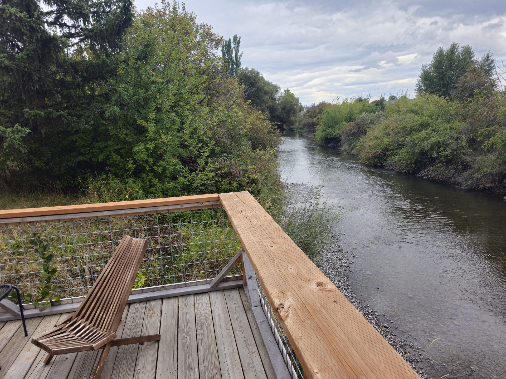 A chair on the riverside deck looking down the Whitefish River